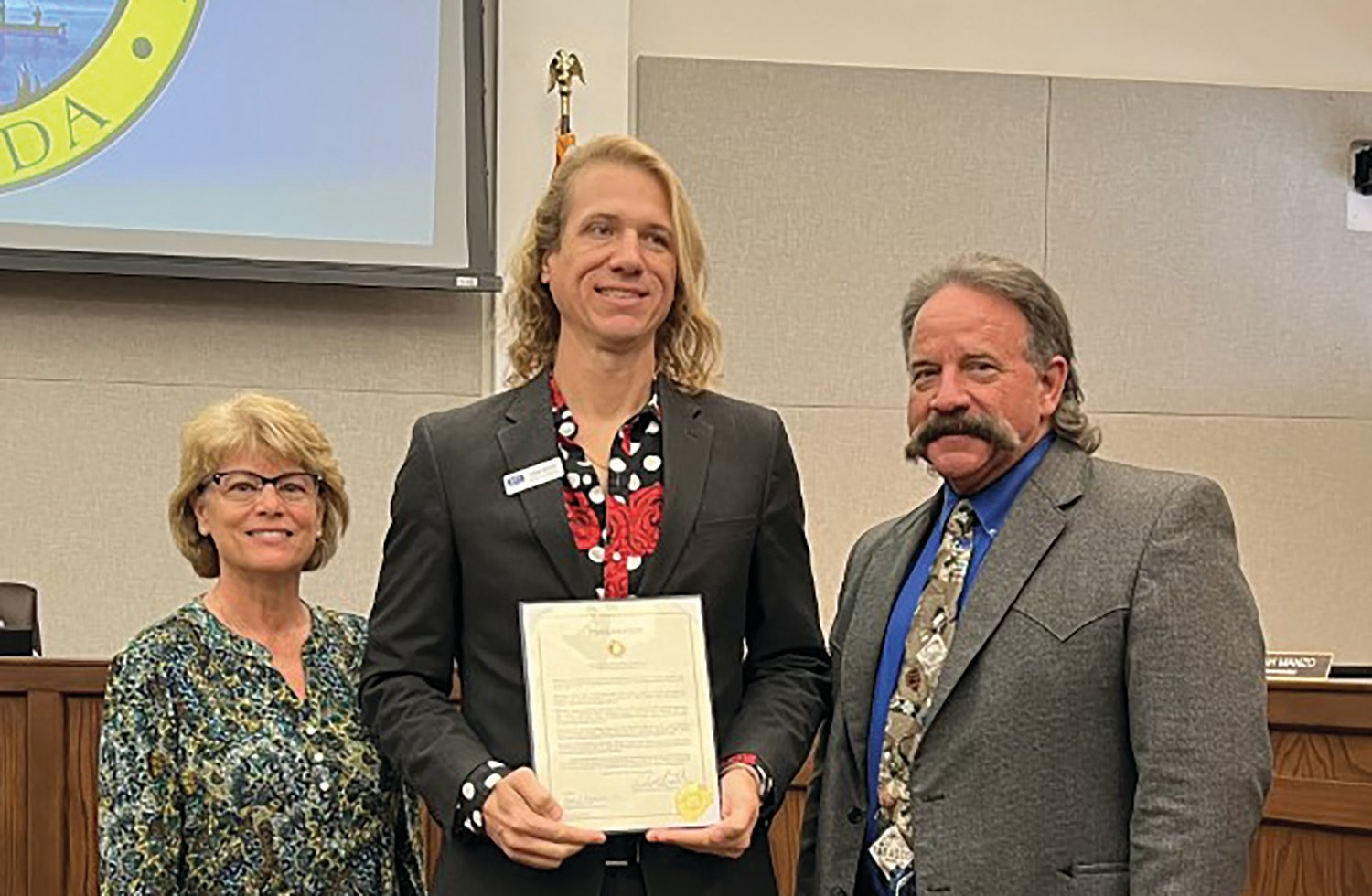 OKEECHOBEE -- At the Jan. 26 meeting of the Okeechobee County Commission, Commissioners Kelly Owens (left) and Brad Goodbread (right) presented Chad Adcock (center) with a proclamation in honor of 211 Helpline Awareness Month.